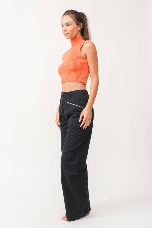 Woman wearing a cropped orange mock neck ribbed knit sweater.