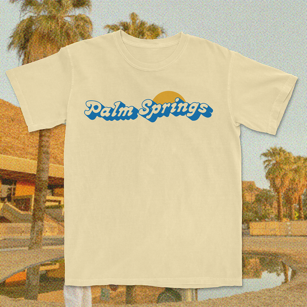 Yellow "Palm Springs" T-shirt with blue text and a sun graphic on a white background.