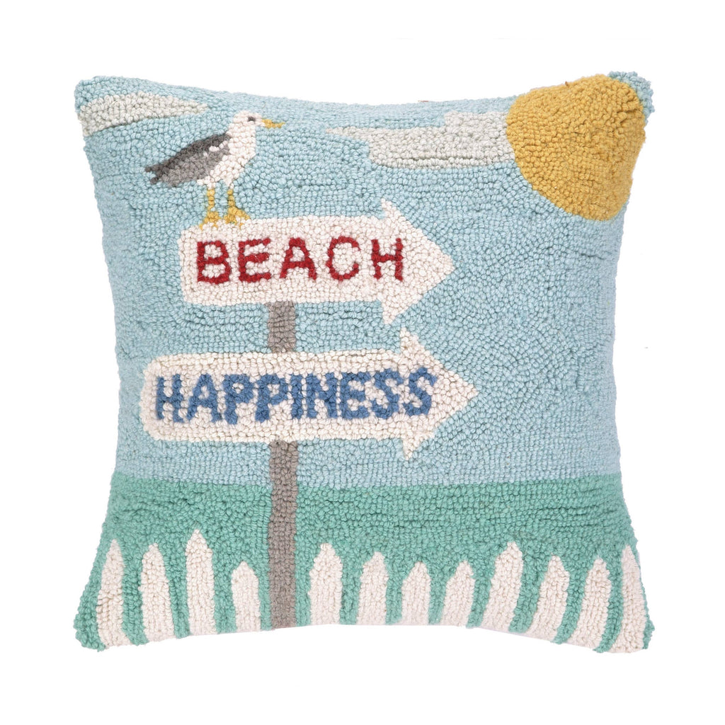 A beach-themed throw pillow with textured design, featuring a seagull on directional signs that read "Beach" and "Happiness" against a blue sky background.