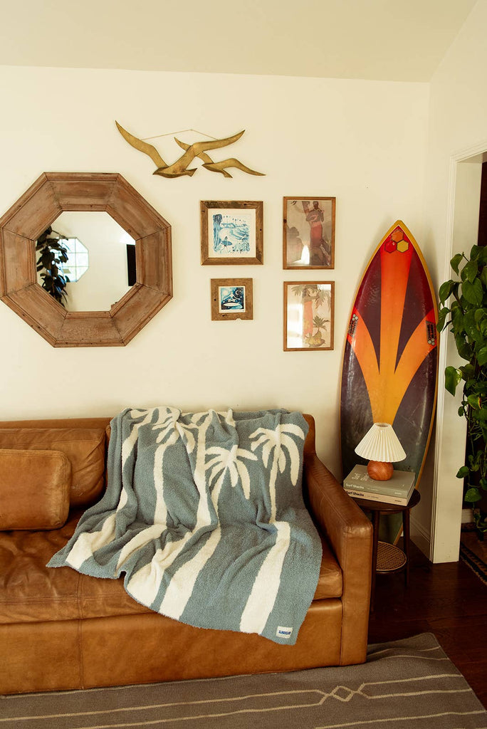 Soft chambray blue plush throw with palm tree design, perfect for cozying up or adding a beachy touch to any space.