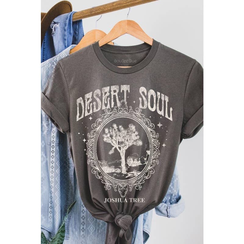 "Desert Soul" graphic t-shirt featuring a Joshua Tree design, available in sage green and charcoal gray, displayed on hangers.