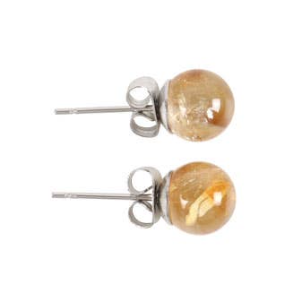 A pair of citrine crystal stud earrings displayed on a matching backing card, held in a hand with a serene background.