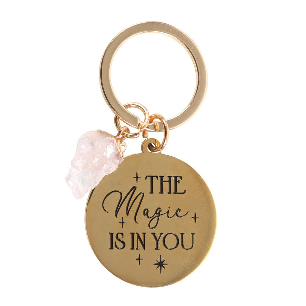 Rose quartz crystal keychain with a gold-tone charm engraved with ‘The Magic Is In You’ text.