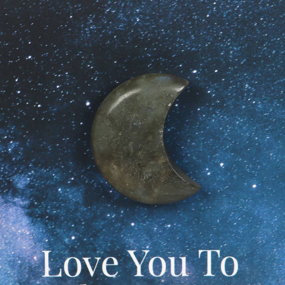 Hand holding a greeting card with a small labradorite crystal crescent moon and ‘Love You To The Moon & Back’ text.