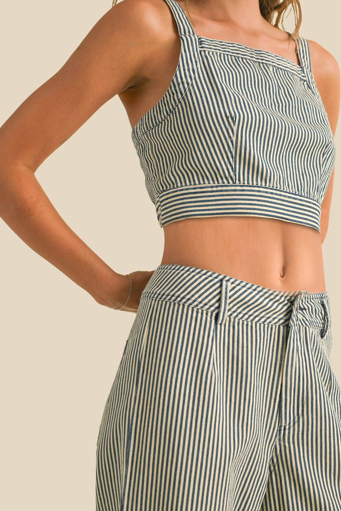 Woman wearing a sleeveless navy and white striped linen crop top with wide straps and a square neckline.