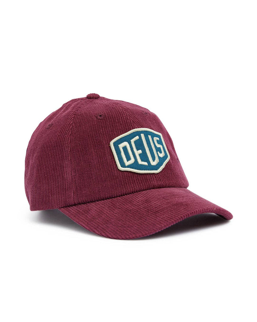 Burgundy corduroy cap with an embroidered "Deus" patch, unstructured design, and adjustable fit.