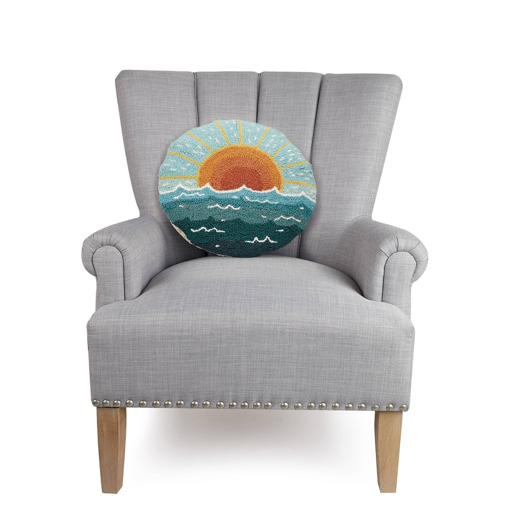 Round cushion with a hand-hooked sunrise over the ocean design in coastal colors.