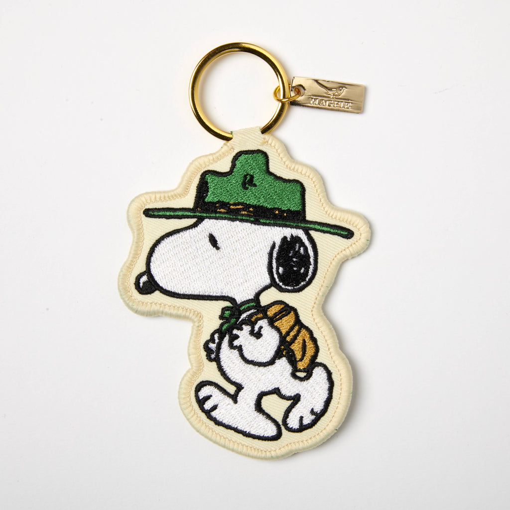 Embroidered Snoopy keychain featuring Snoopy in a green scout hat and backpack, attached to a gold ring with a Magpie tag.