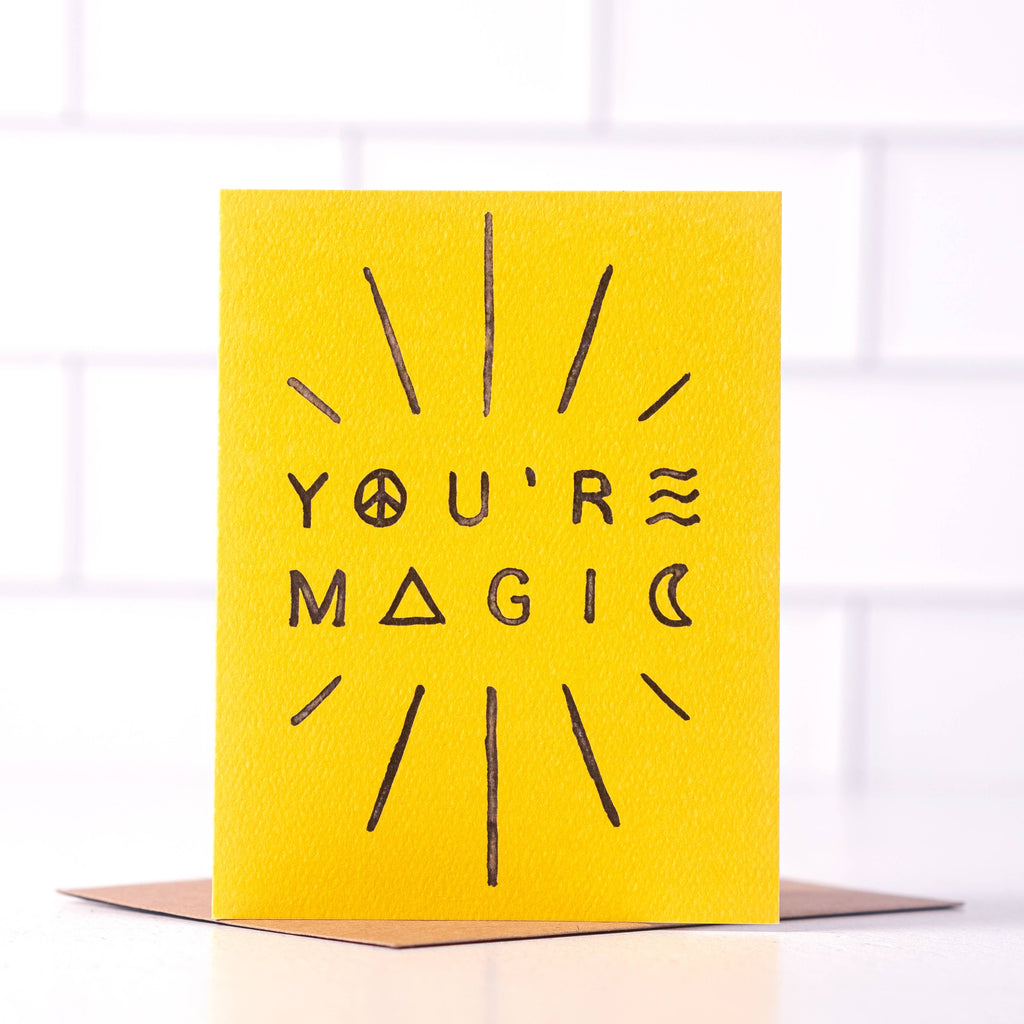 Bright yellow card with black text and symbols saying ‘You’re Magic,’ surrounded by radiating lines.