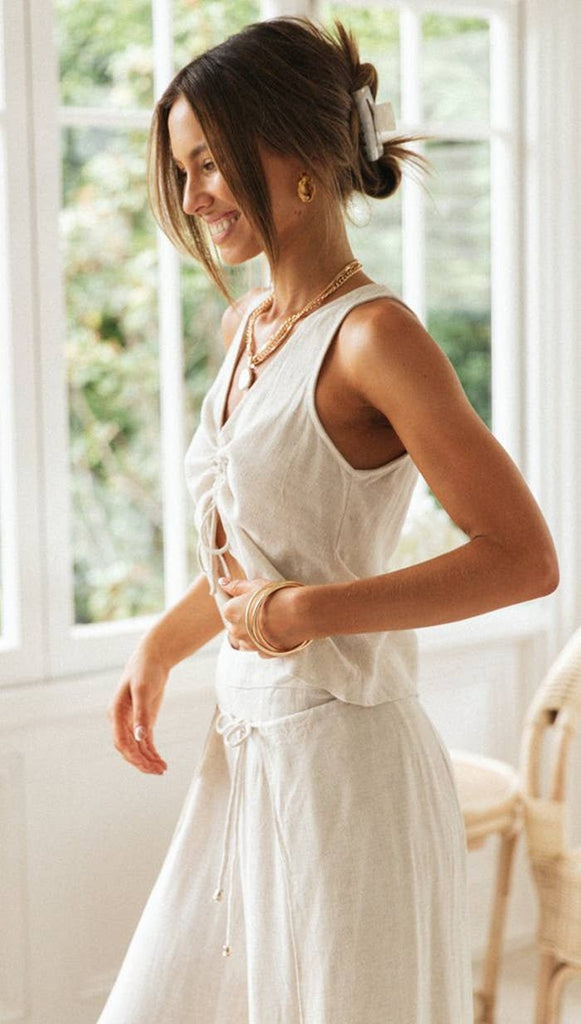 Woman wearing a Sun-Kissed Drawstring Crop Top in a light beige color, featuring a front cinched drawstring detail, paired with wide-leg pants.