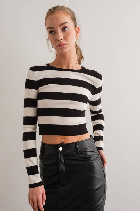 Woman wearing a black and white striped slim-fit crop top with long sleeves and a round neck.