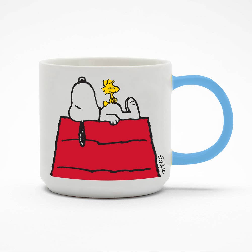 Ceramic mug featuring Snoopy and Woodstock resting on a red doghouse with a light blue handle.