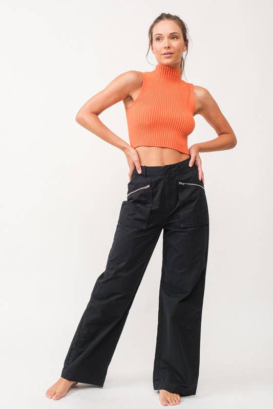 Woman wearing a cropped orange mock neck ribbed knit sweater.