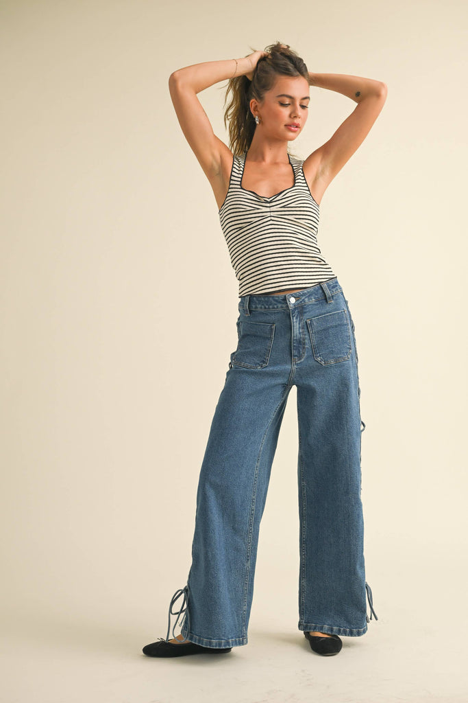 Striped knit tank top with a scoop neckline and ruched bust, styled with high-waisted denim for a casual yet chic look.