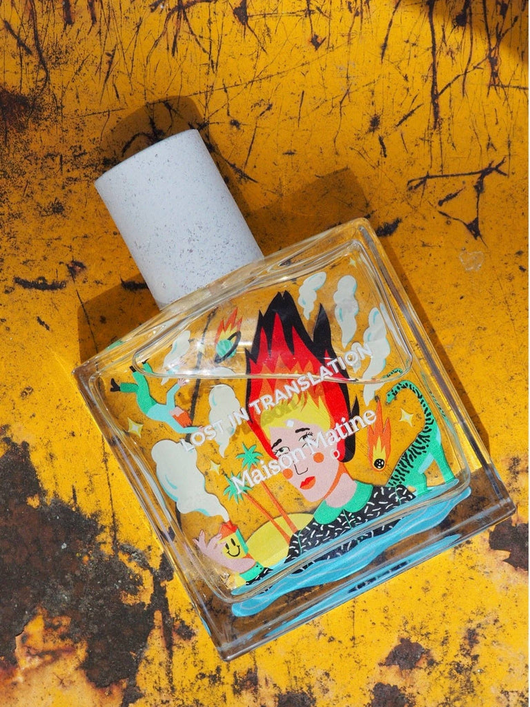 Maison Matine Lost in Translation perfume bottle with bold illustrated design, placed on vibrant yellow textured surface.