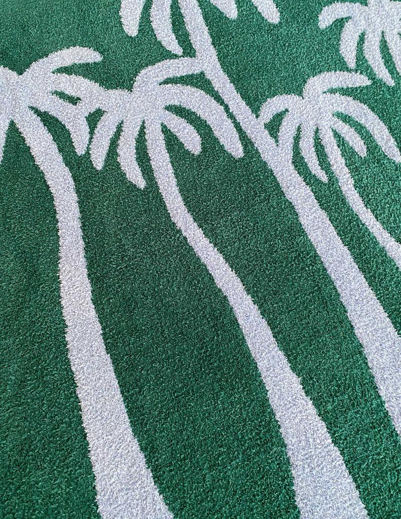 A teal and light blue throw blanket featuring a palm tree design, made of soft and plush material.