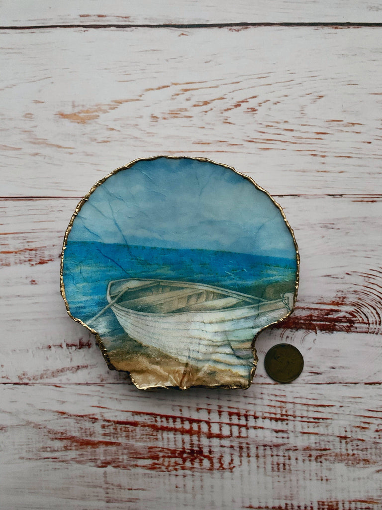 Decorative shell featuring a tranquil rowboat scene by the sea with gold edges, ideal for home decor or as a unique gift.