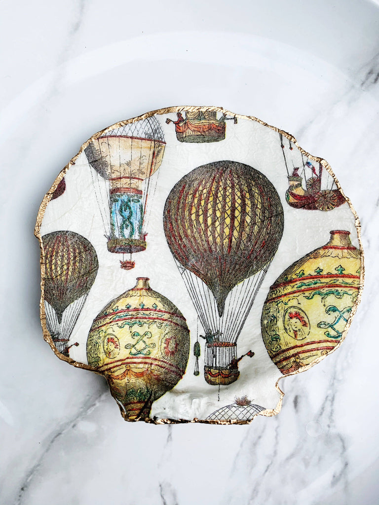 Decorative shell featuring intricate hot air balloon designs with gold edges, perfect for adding a whimsical touch to your home decor.