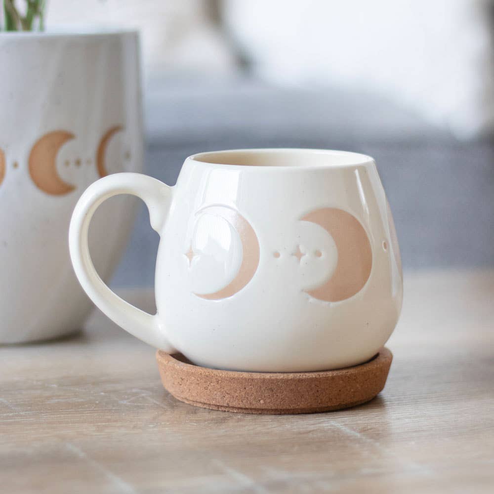 Ivory mug with moon phase design and cork coaster.