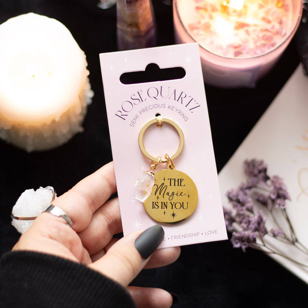 Rose quartz crystal keychain with a gold-tone charm engraved with ‘The Magic Is In You’ text.