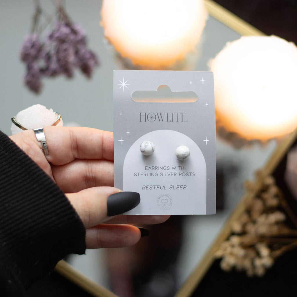 Howlite crystal stud earrings on a matching backing card held by a hand with black nail polish.